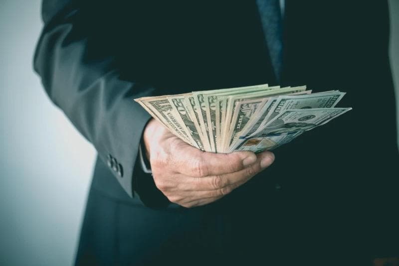 Man in suit holding Legal Funding money