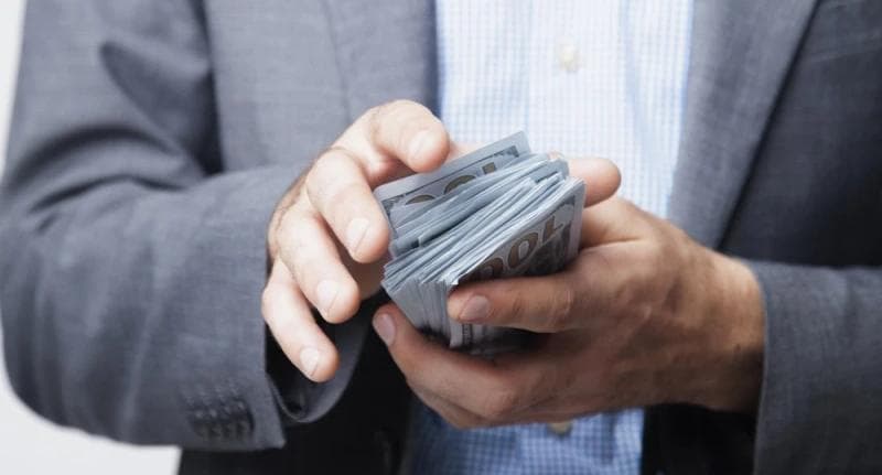Hands of man in suit holding pre-settlemend funding cash