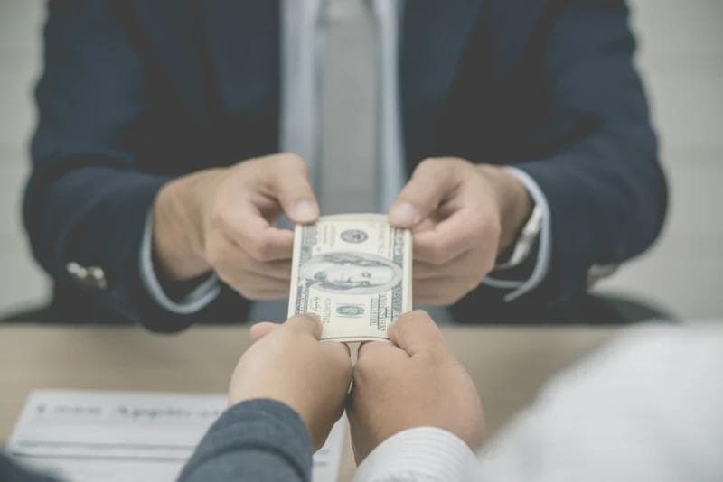 Man in suit receiving post-settlement funding money from two other men