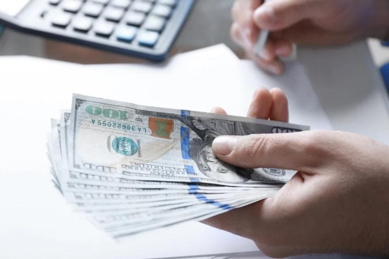 Man holding Legal Funding money with left hand and signing document with right hand