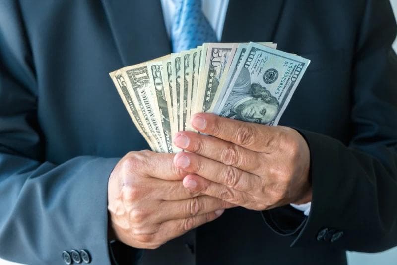 Man in suit holding Legal Funding money