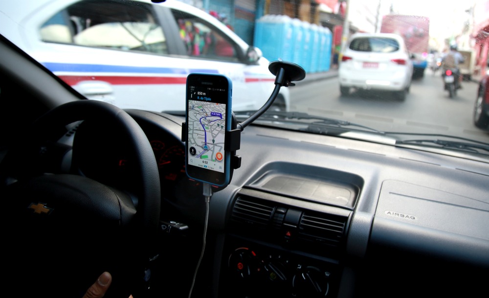 An image of a dashboard taken from inside the car. A cell phone in a dashboard mount can be seen with a map on its screen. Rockpoint Legal Funding is a great source of pre-settlement funding for plaintiffs who have been imjured in a rideshare vehicle accident.