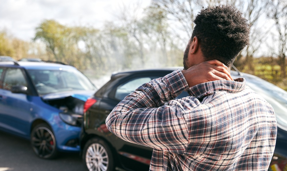 Man rubs neck after a rear-end accident. His injuries can be treated with funding provided by the best legal funding company.