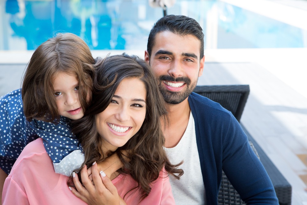 A mother, father and young child. They're brightly smiling at the camera. They can receive pre-settlement funding from Rockpoint Legal Funding to help with expenses before their case settles.