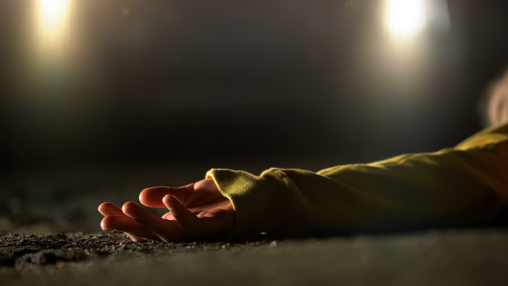 A person is lying in the road at night. Only their arm is visible with the palm up. There are headlights visible in the background of the image. Rockpoint Legal Funding provides cash advances for plaintiffs in wrongful death lawsuits.
