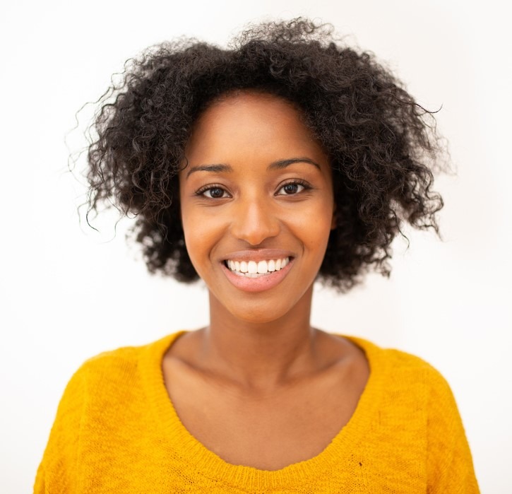 Headshot of a young black woman smiling. She is wearing a yellow sweater. She's happy because she got cash fast with Rockpoint Legal Funding's pre-settlement services.