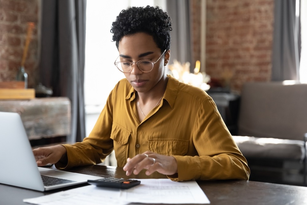 black woman using computer to calculate her budget